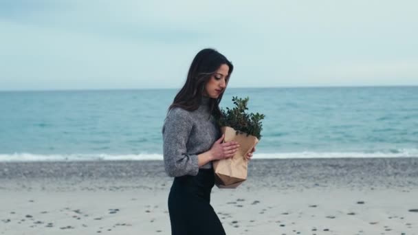 Jong meisje loopt met een papieren zak en een bos van bladeren en takken — Stockvideo