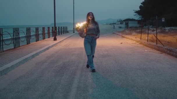 Genç kız elinde bir buket çiçek ve parti ışıklarıyla yürüyor. — Stok video
