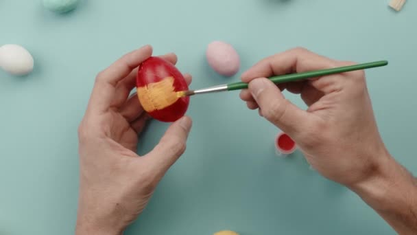 A mão de um homem está pintando ovos de Páscoa coloridos — Vídeo de Stock