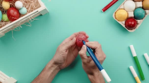 La mano de un hombre está pintando huevos de Pascua de color — Vídeos de Stock