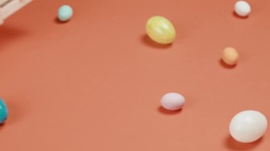 El, turuncu arka plana Paskalya yumurtası dolu bir kutu yerleştiriyor.