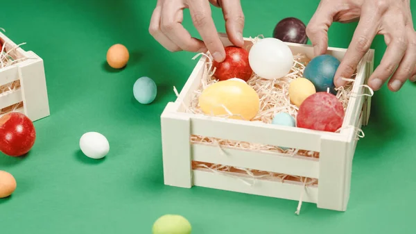 Tangan seorang pria meletakkan telur Paskah berwarna di keranjang. — Stok Foto
