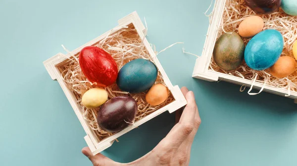 Tangan seorang pria meletakkan telur berwarna Paskah di kotak — Stok Foto