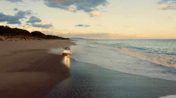 Off road white car is running on the beach near the ocean. — Stock Photo, Image