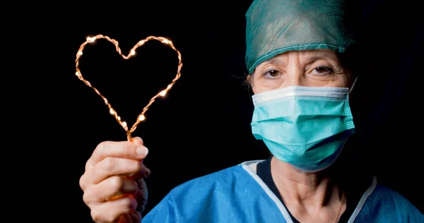 Lekarz sprawia, że symbol serca z maską i czarnym tle — Zdjęcie stockowe