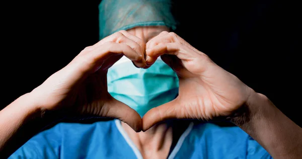 Doktor dělá symbol srdce s maskou a černým pozadím — Stock fotografie