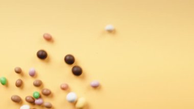 Sarı arka planda yuvarlanan Paskalya çikolatalı yumurtalar