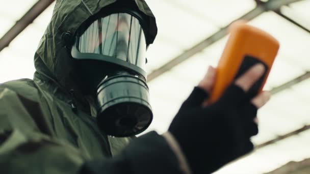 Hombre con máscara de radiación y contador geiger comprueba un sitio nuclear — Vídeo de stock
