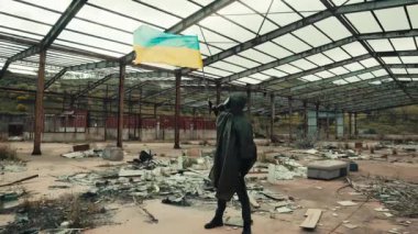 Gaz maskeli asker savaş deposunda Ukrayna bayrağı sallıyor.