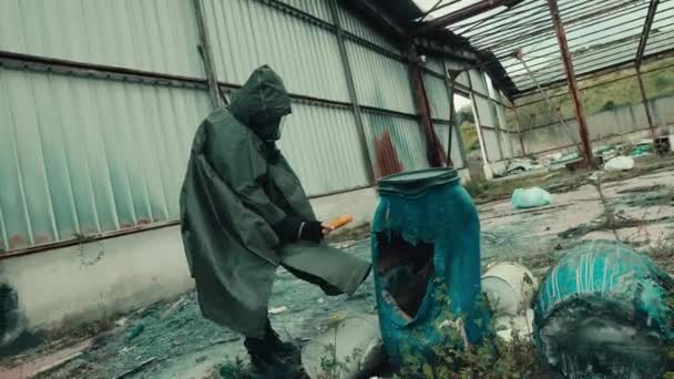 Gaz maskeli bir adam, radyasyon seviyesini bir kulübede Gayger sayacıyla kontrol ediyor. — Stok video