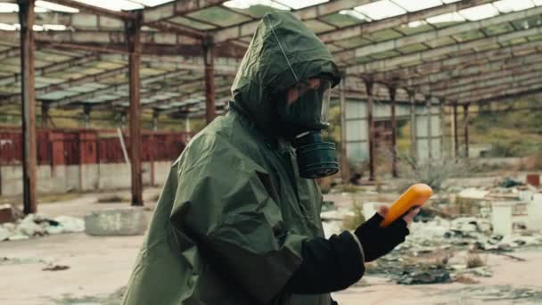 Man met stralingsmasker en geigerteller controleert een nucleaire locatie — Stockvideo