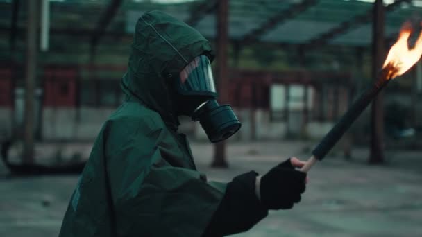 Gaz maskeli bir asker, meşaleyle yıkılan bir binada. — Stok video