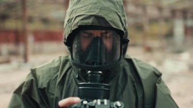 Gaz maskeli ve kameralı bir asker bombanın patlamasını fotoğraflıyor.