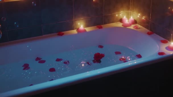 Pétales rouges et bulles de savon tombent dans une baignoire romantique — Video