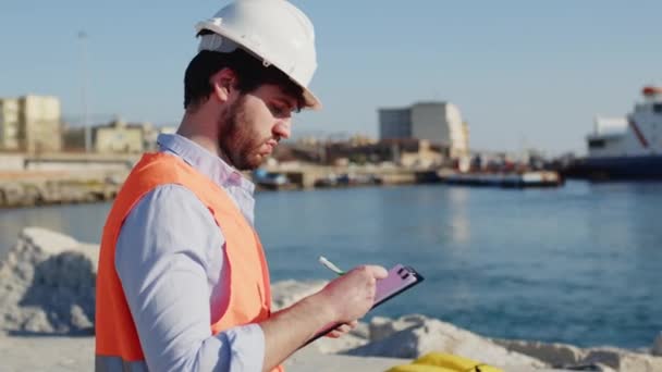 Tengerészeti mérnök minőség-ellenőrzés a kikötőben egy város közelében az óceán — Stock videók