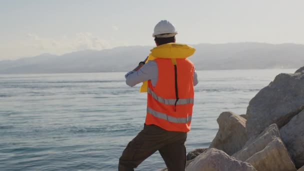 Mladý námořní inženýr ovládá moře z přístavu dalekohledem — Stock video