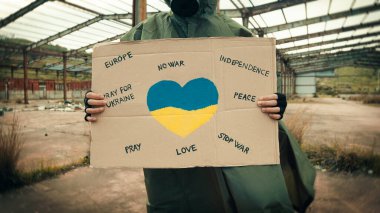 Gaz maskeli ve Ukrayna 'da savaş için barış pankartı olan bir adam.