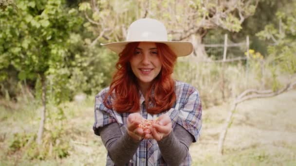 Νεαρή αγρότισσα κρατά σπόρους καλαμποκιού στο χέρι της στην ύπαιθρο — Αρχείο Βίντεο