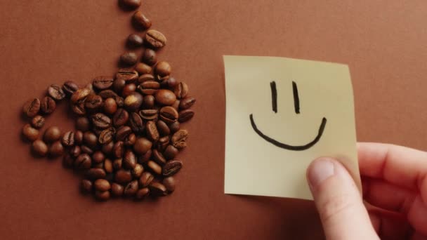 Etiqueta de sonrisa en taza de café hecho de frijoles asados. — Vídeo de stock