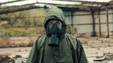 Savaş tarafından yıkılan bir binada gaz maskeli bir adam selamlıyor.