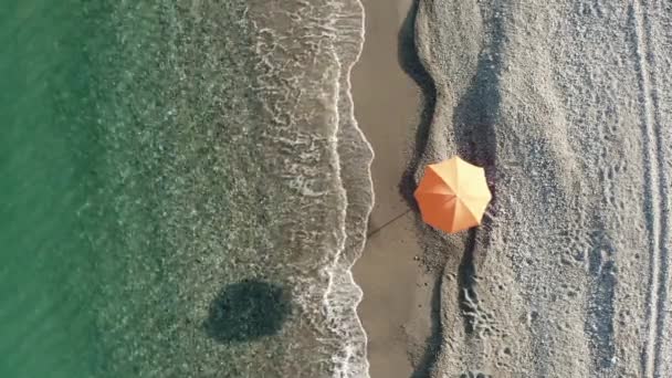 Orange umbrella near the calm waves of the sea at Summer — Vídeos de Stock