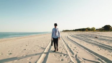 Business guy walks at the beach with virtual reality simulation of desert
