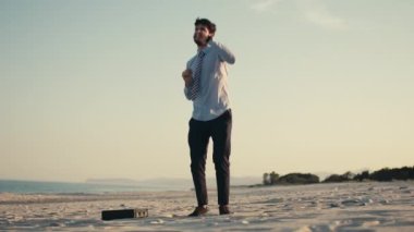 İş adamı kumsalda dans eder kilometre taşına ulaşmak için.