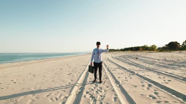 Business guy walks at the beach with virtual reality glasses — Stock video