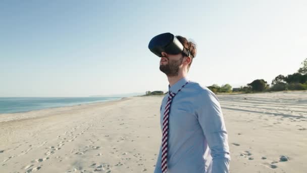 Business guy with shirt and tie tries on virtual reality glasses at the beach — Stock video