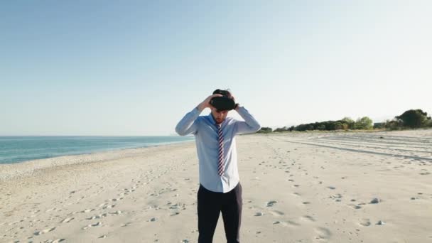 Zakenman in blauw shirt draagt virtual reality bril op het strand — Stockvideo
