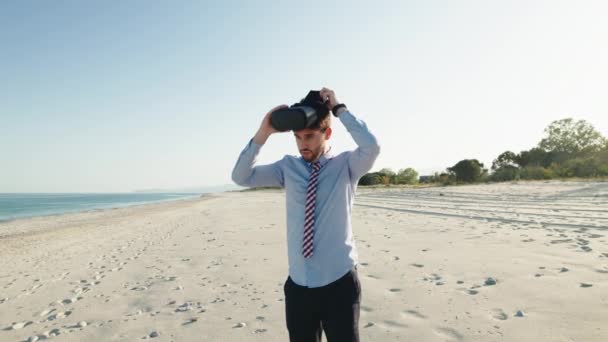 Hombre de negocios con camisa lleva gafas de realidad virtual en la playa — Vídeo de stock