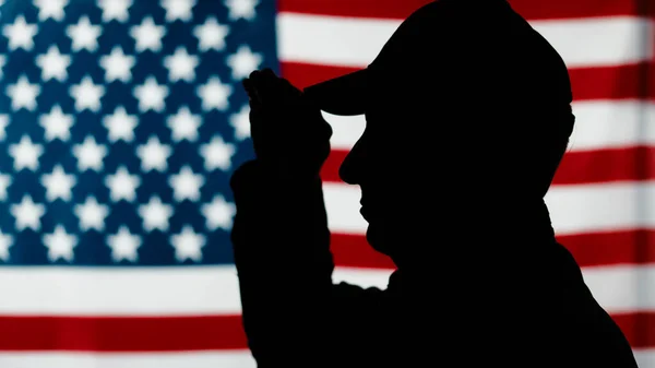 American military veteran stands at attention with military flag salute. – stockfoto
