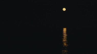 Hilal ay, gece sakin ve rahatlatıcı denize yansıyor.