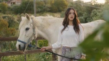 Genç, güzel bir İtalyan model kız kırsaldaki çiftlikte bir atla poz veriyor. El kamerasıyla çekim.