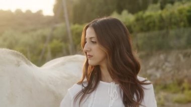 Genç, güzel bir İtalyan model kız kırsaldaki çiftlikte bir atla poz veriyor. El kamerasıyla çekim.