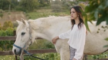 Genç, güzel bir İtalyan model kız kırsaldaki çiftlikte bir atla poz veriyor. El kamerasıyla çekim.