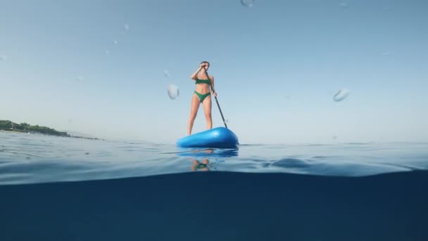 夏天的女孩站在海面上的船桨上 水下射箭 — 图库视频影像