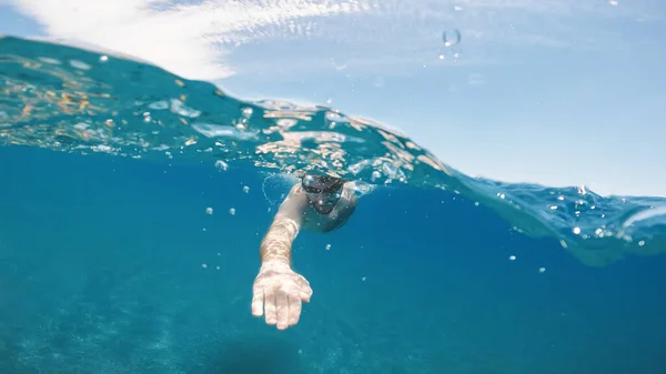 Boy swims freestyle in the open ocean. Underwater shoot