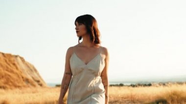 Young girl in white dress walks in a yellow field.