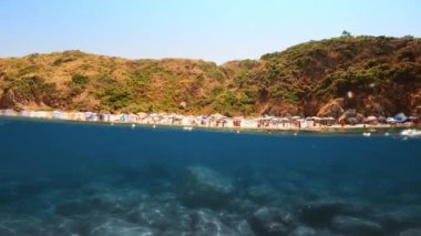 Sea with beach umbrellas seen from underwater.