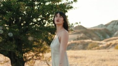 Young girl has fun in the countryside near a tree in the nature in Summer.