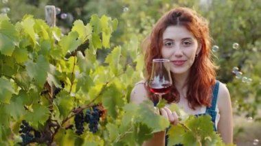 Young beautiful girl with goblet of red wine near the vineyards with quality grapes