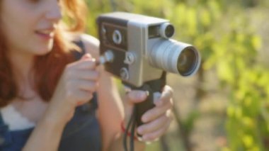 Young photographer girl shoots video with vintage film camera