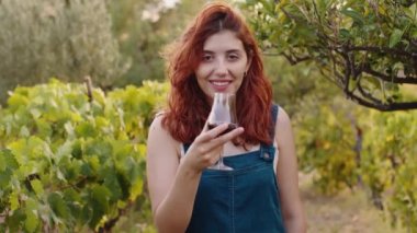 Young beautiful girl with goblet of red wine near the vineyards with quality grapes