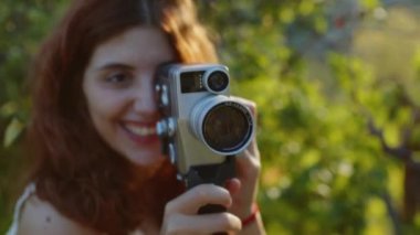 Young photographer girl shoots video with vintage film camera