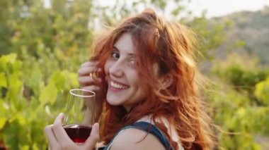 Young beautiful girl with goblet of red wine near the vineyards with quality grapes