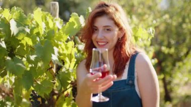 Young beautiful girl with goblet of red wine near the vineyards with quality grapes