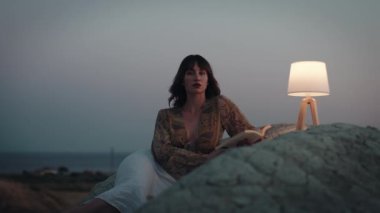 Beautiful girl enjoy the sunset on the mountain in the evening with abat jour lamp on the stones
