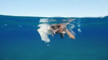 Boy swimmer passes between the plastic of a polluted sea.