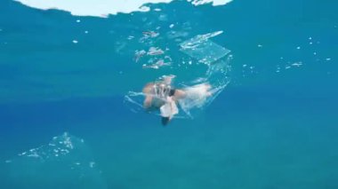 Boy swimmer passes between the plastic of a polluted sea.